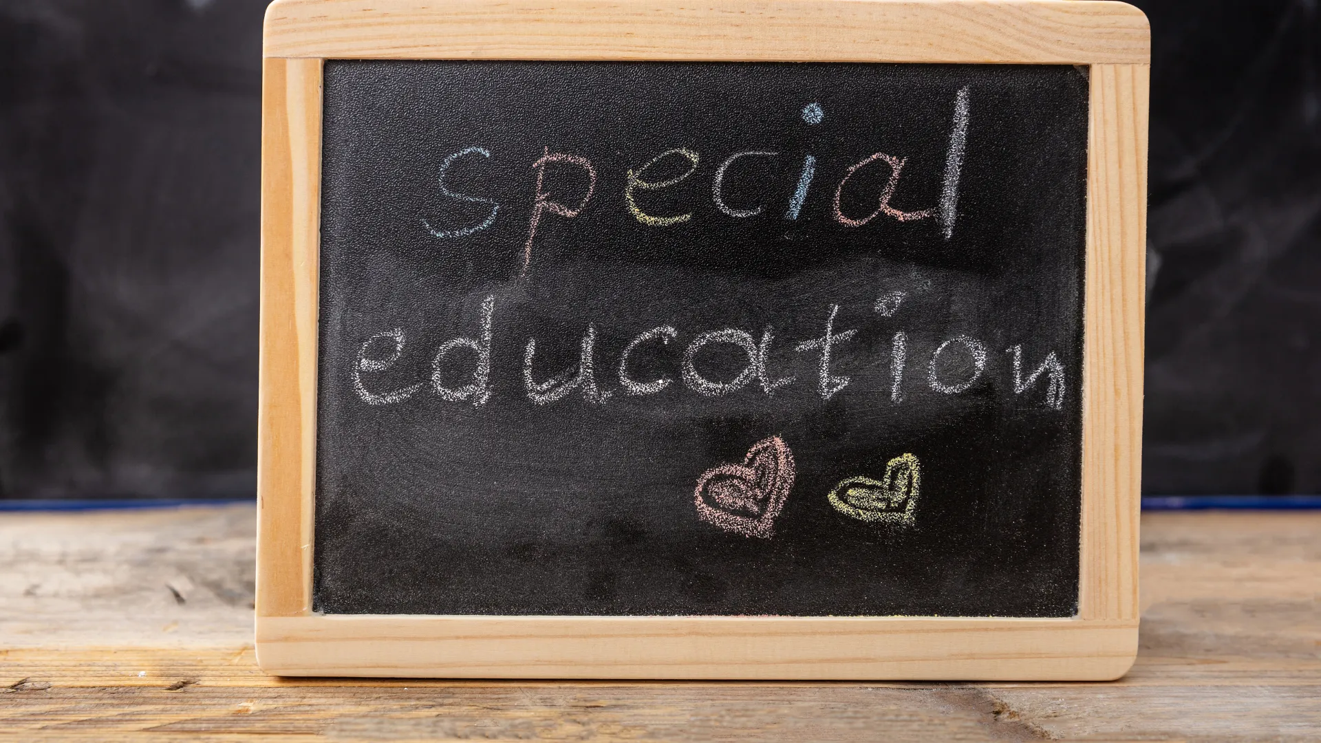 Blackboard with 'special education' written in colourful chalk and two heart drawings