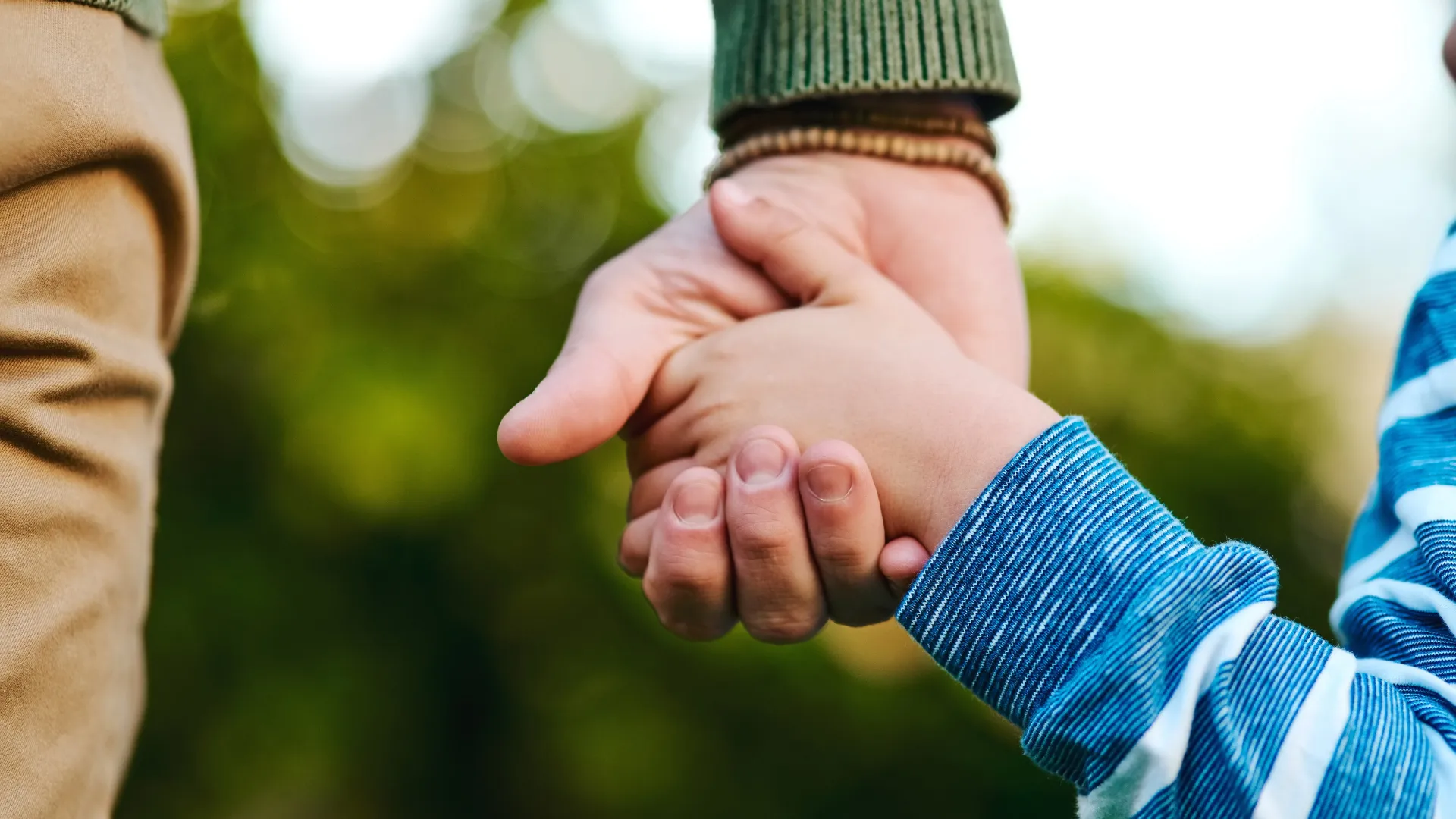 A close up image of an adult holding a child's hands