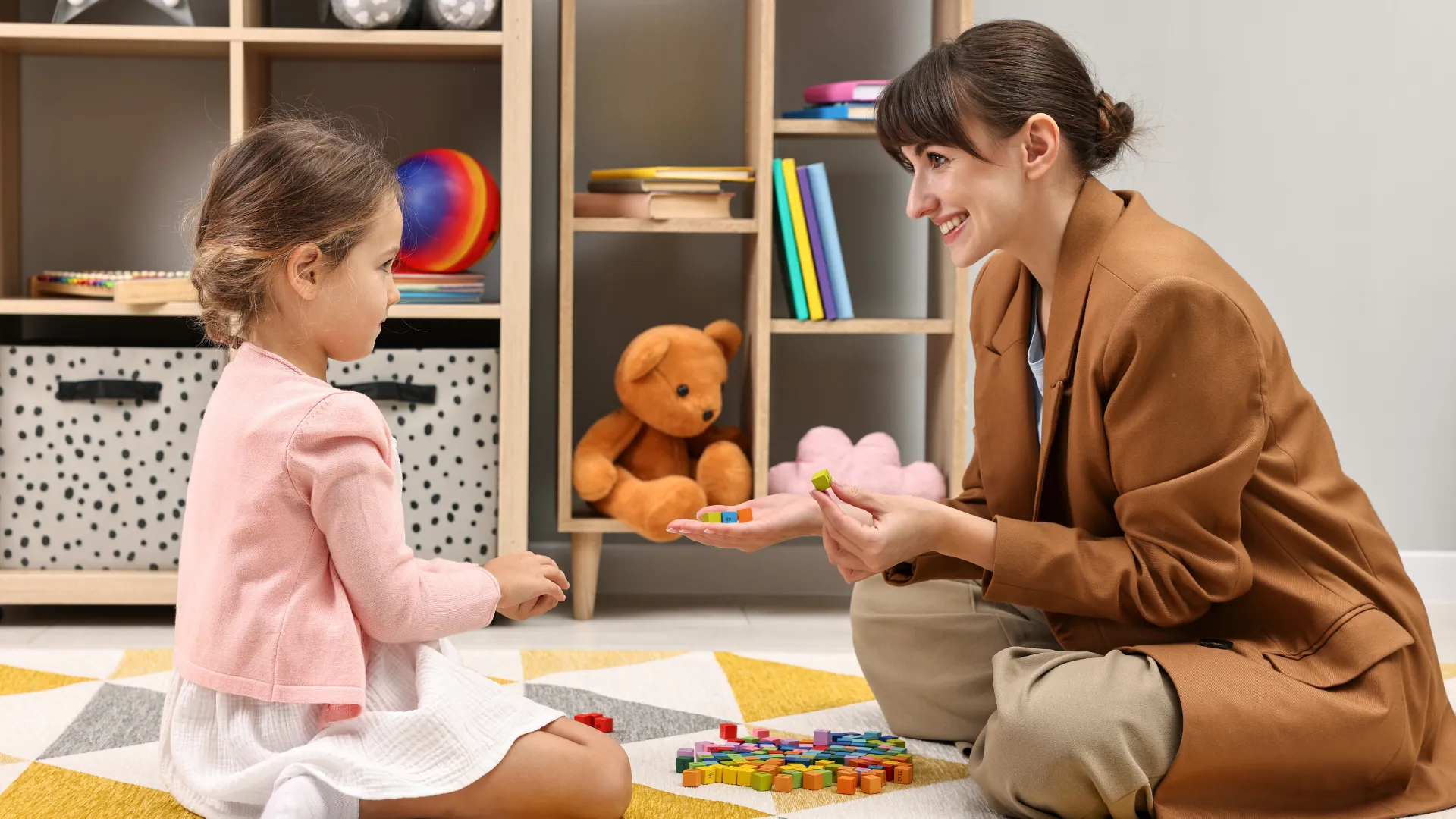 A child and an adult playing with colourful blocks in a classroom