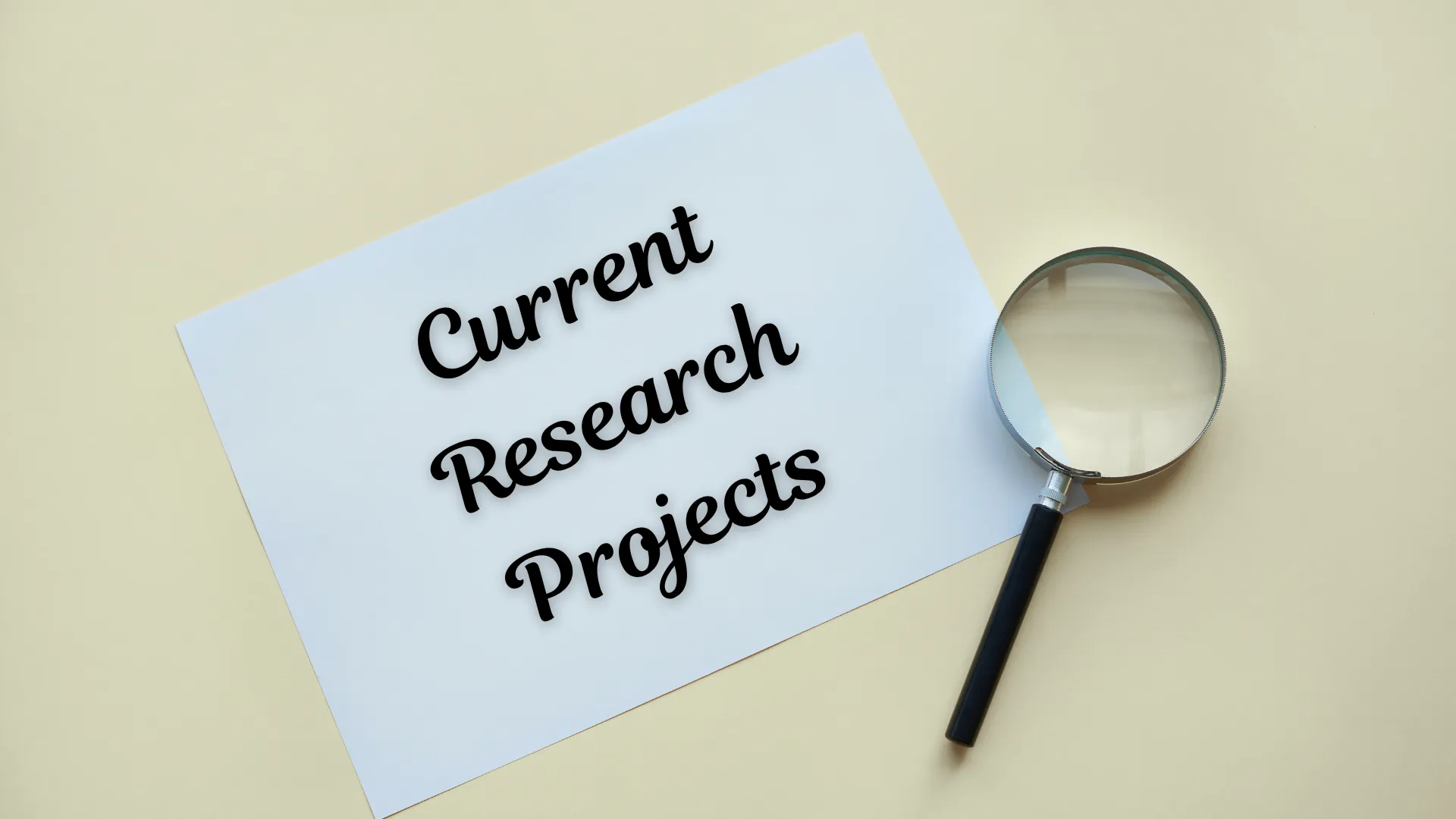A piece of paper with the text 'Current Research Projects' next to a magnifying glass.