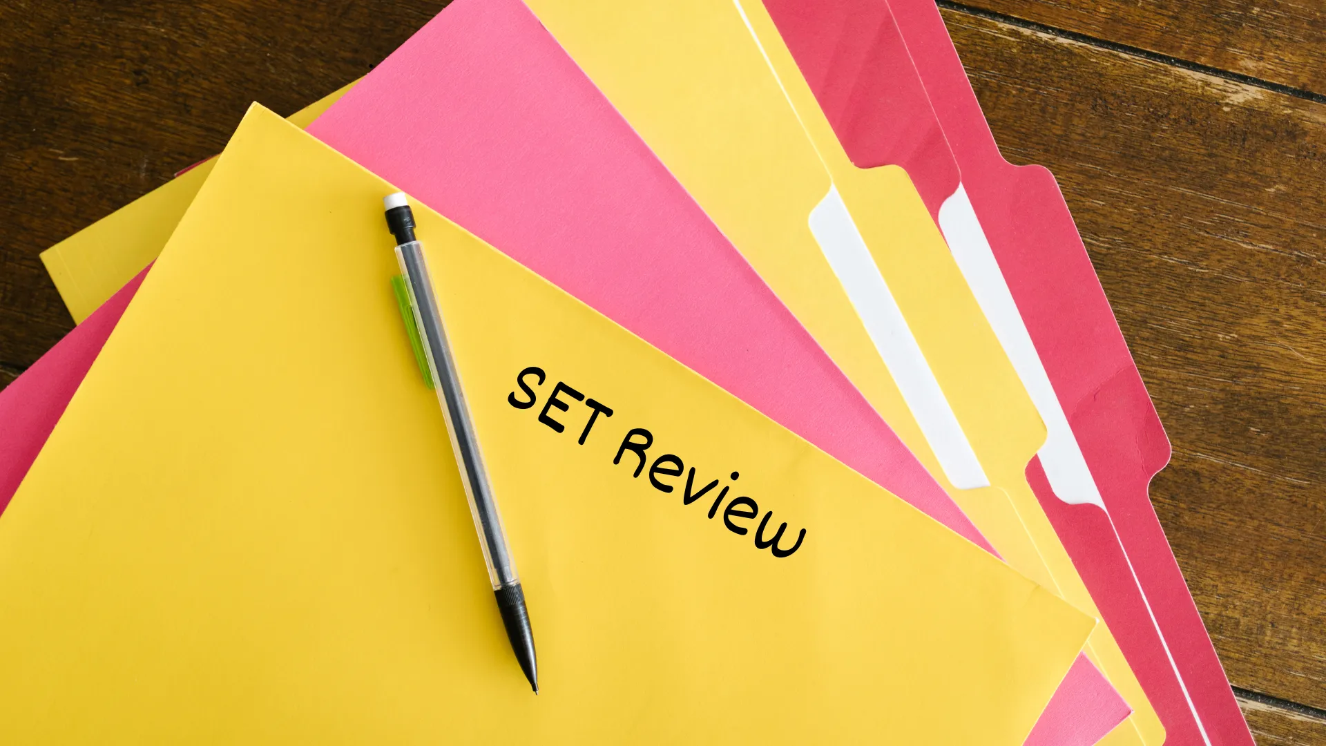 A set of colourful folders with a pen placed on top, and the text "SET Review" written on one of the folders.