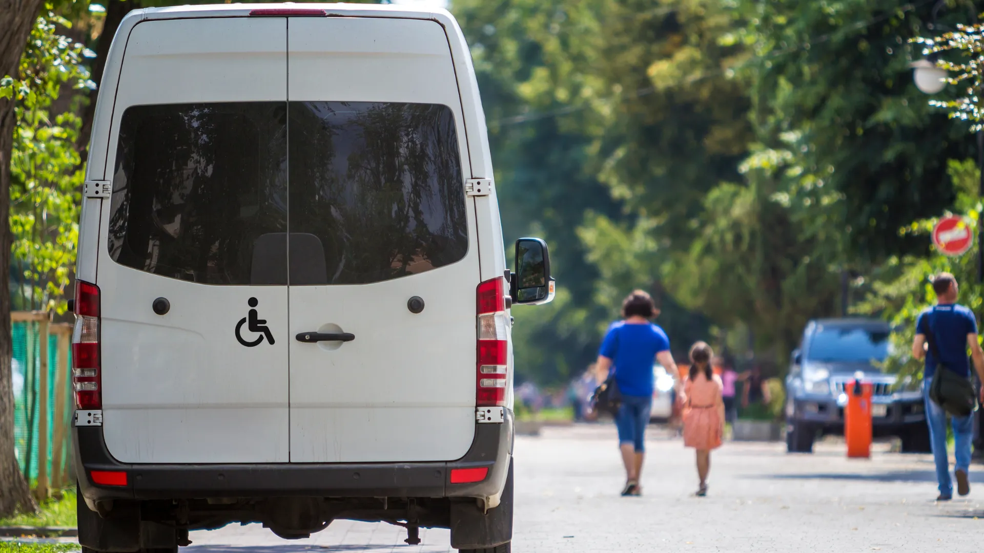 A white van with a wheelchair accessibility symbol parked on a street
