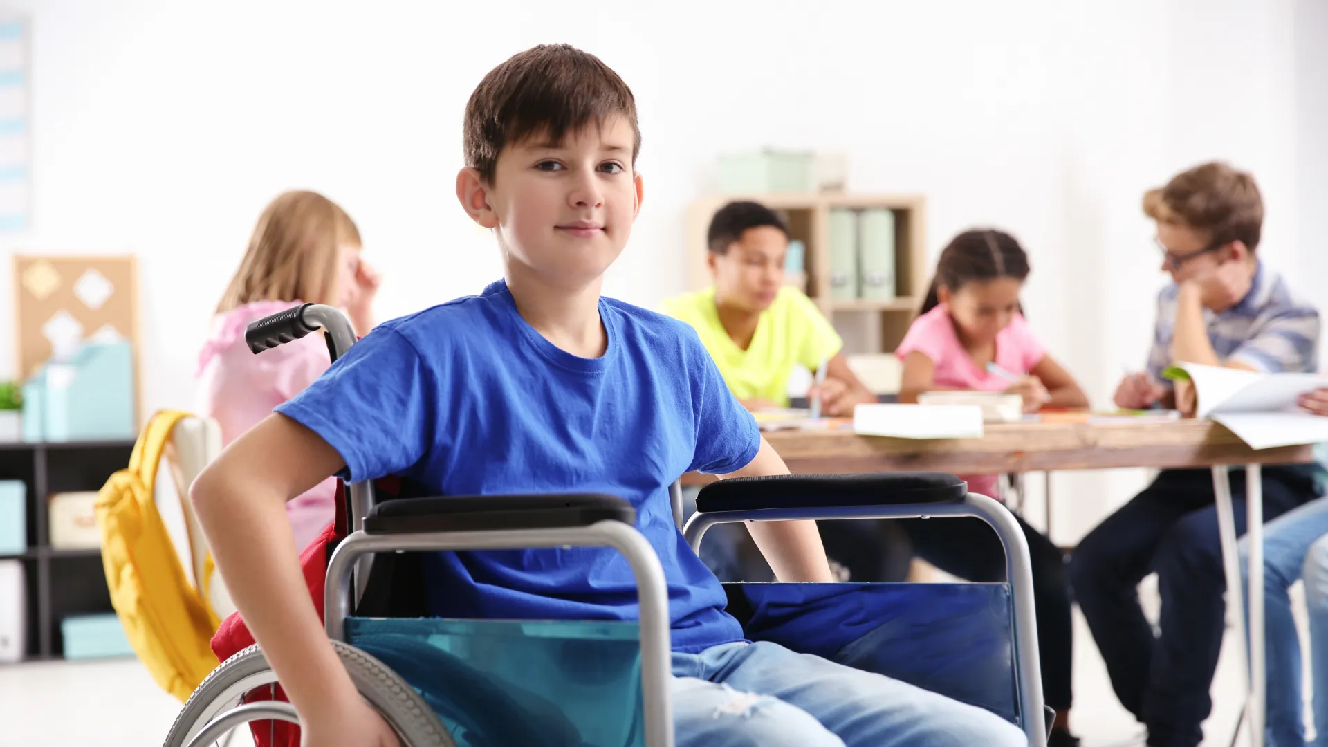A child in a wheelchair in a classroom with other children