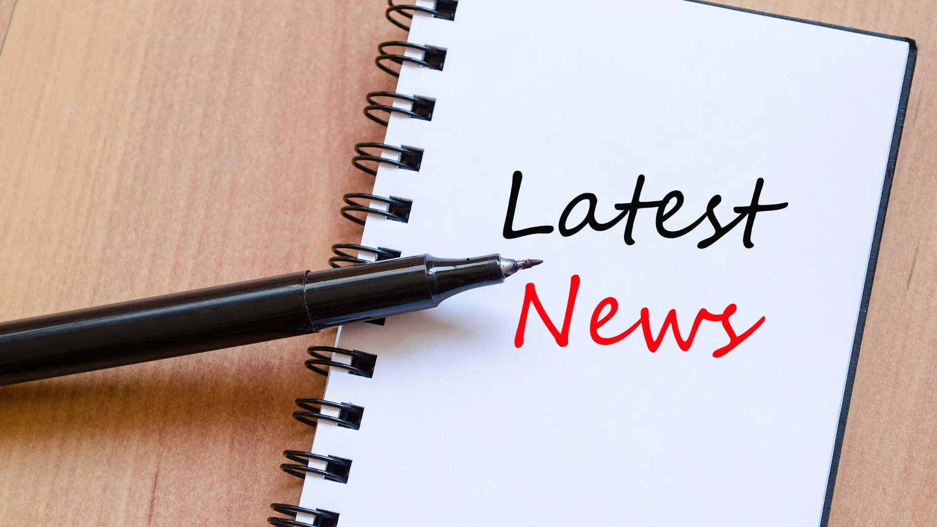 Notebook with the words "Latest News" and a black pen.