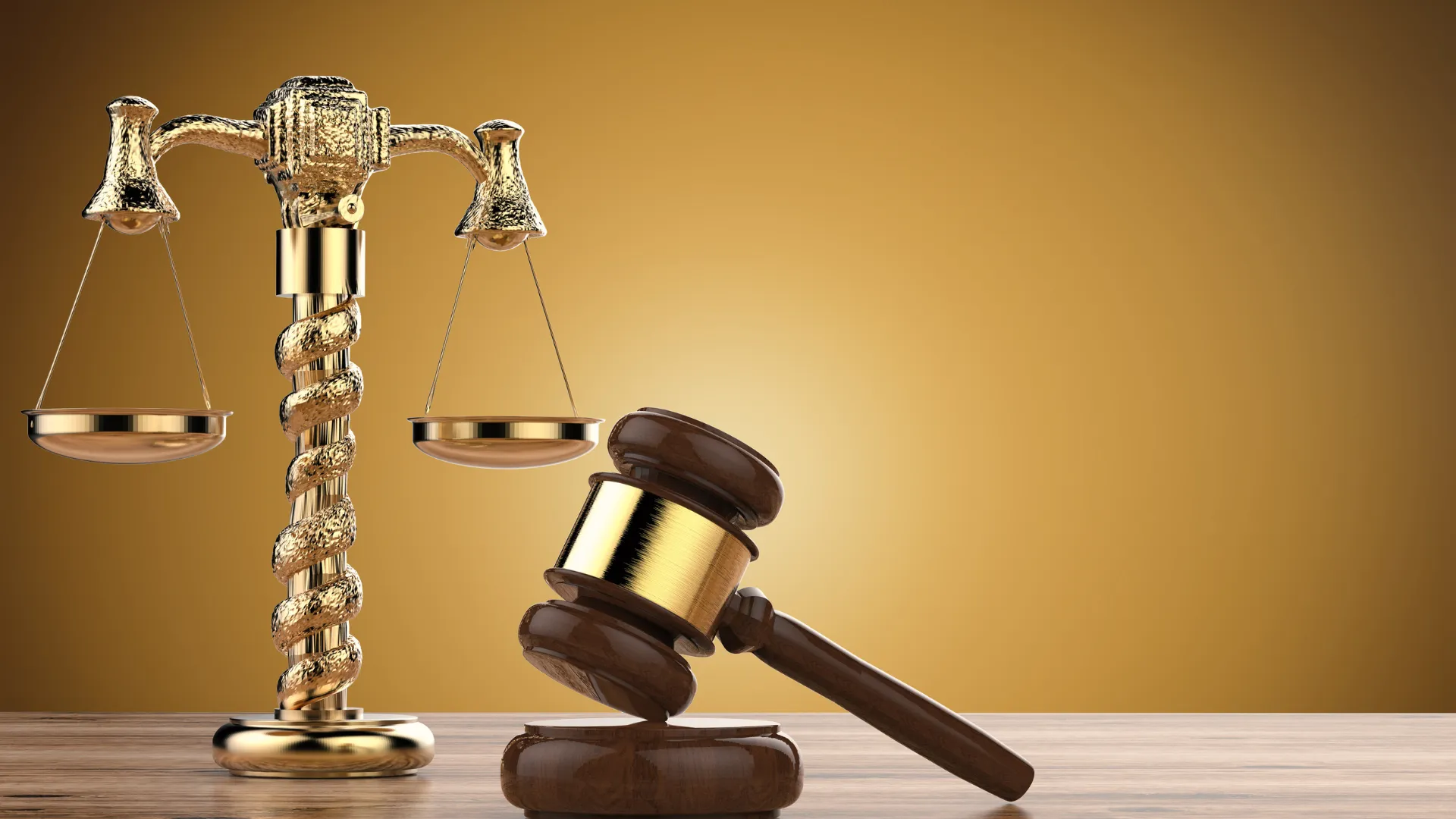 Golden scales of justice and a judge’s gavel on a wooden table