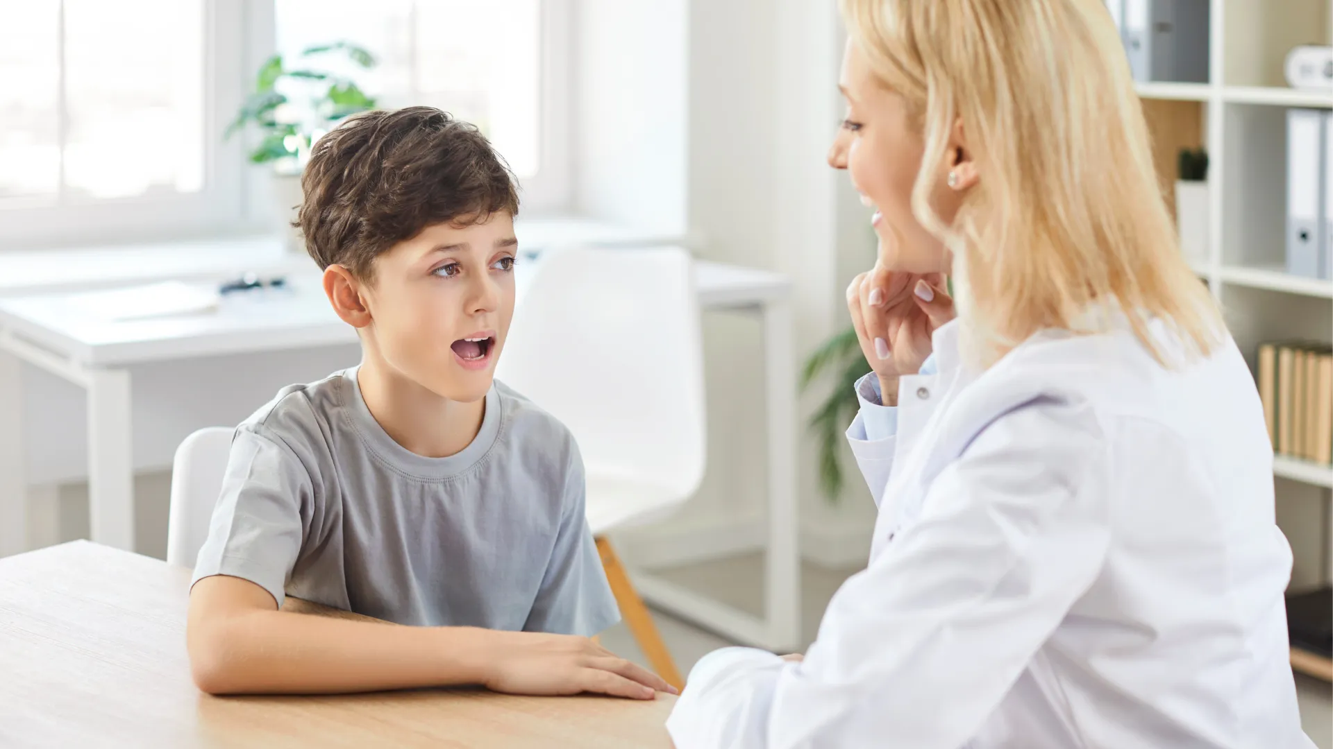 Child talking with a visiting teacher at a desk