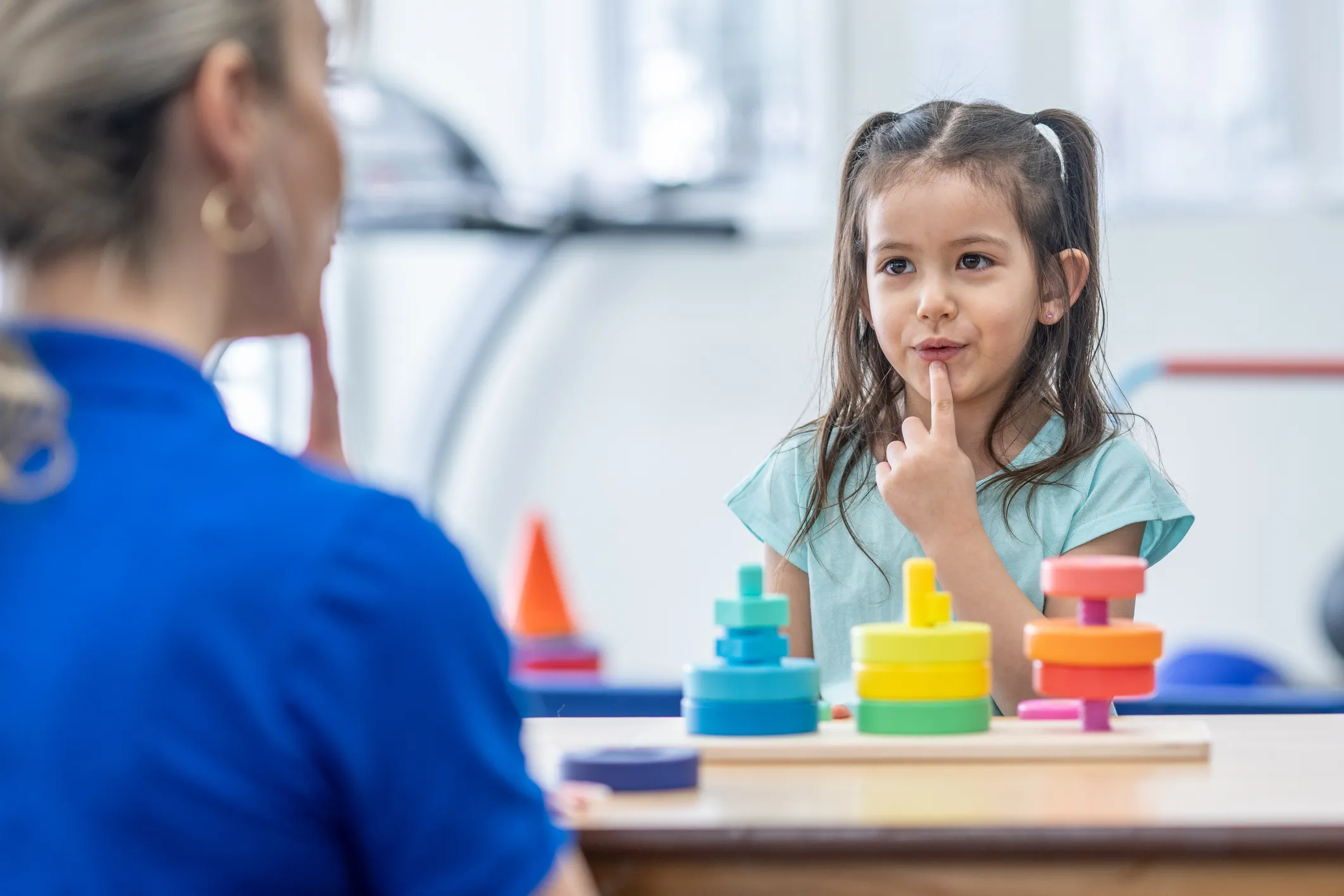Child participating in a learning activity using sign language with an adult