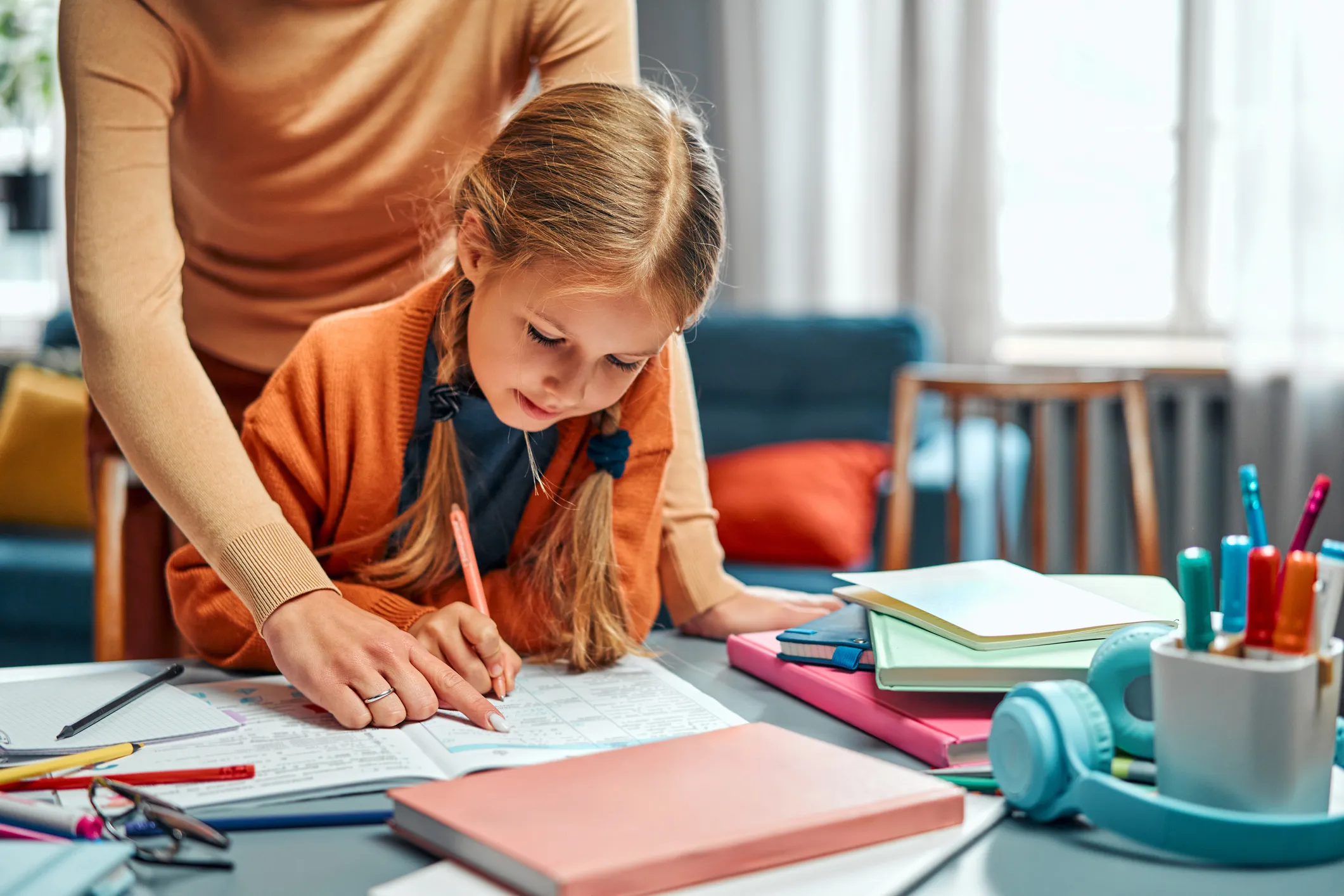 Adult helping a child with homework at a desk