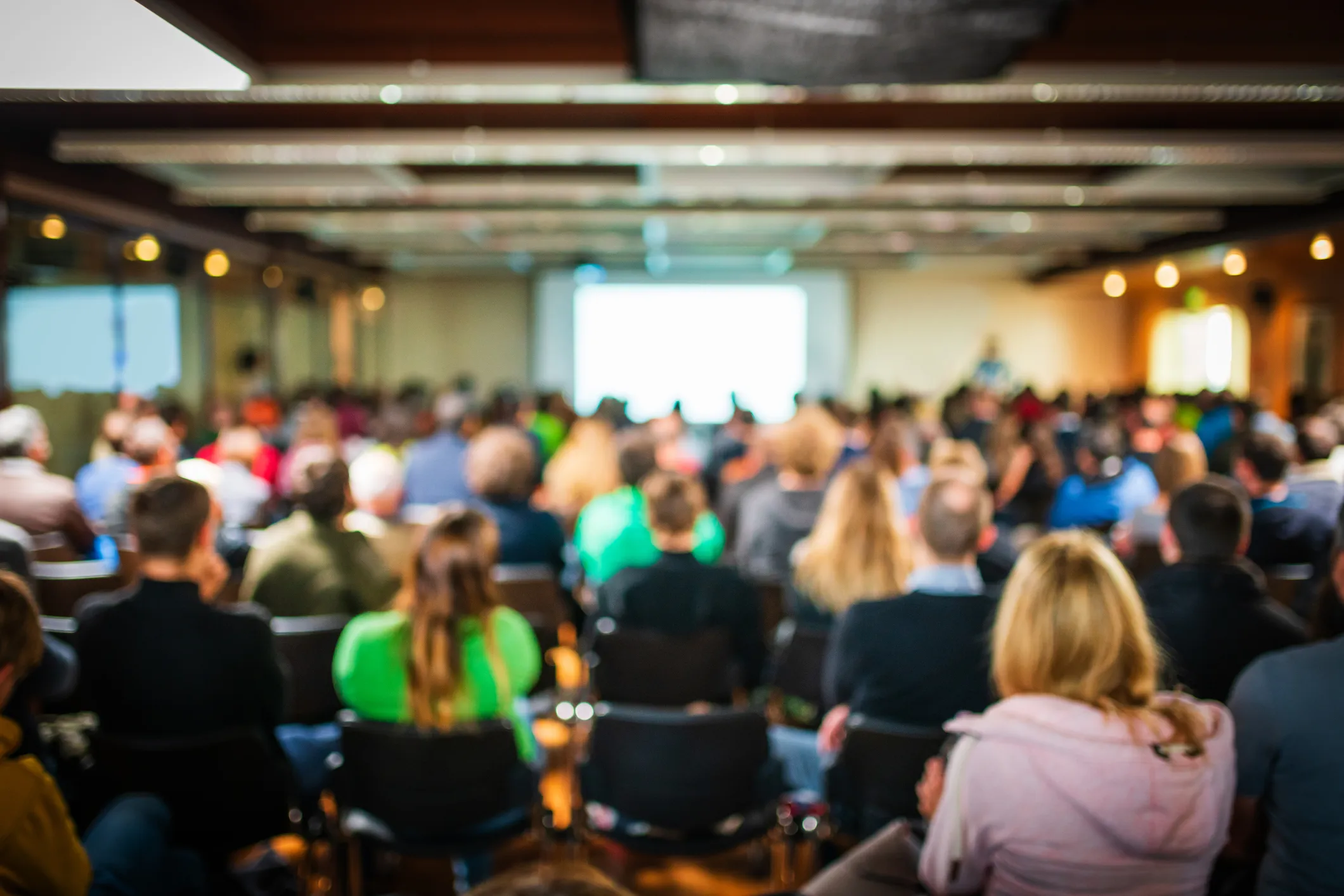 Audience seated in a conference room facing a presentation screen