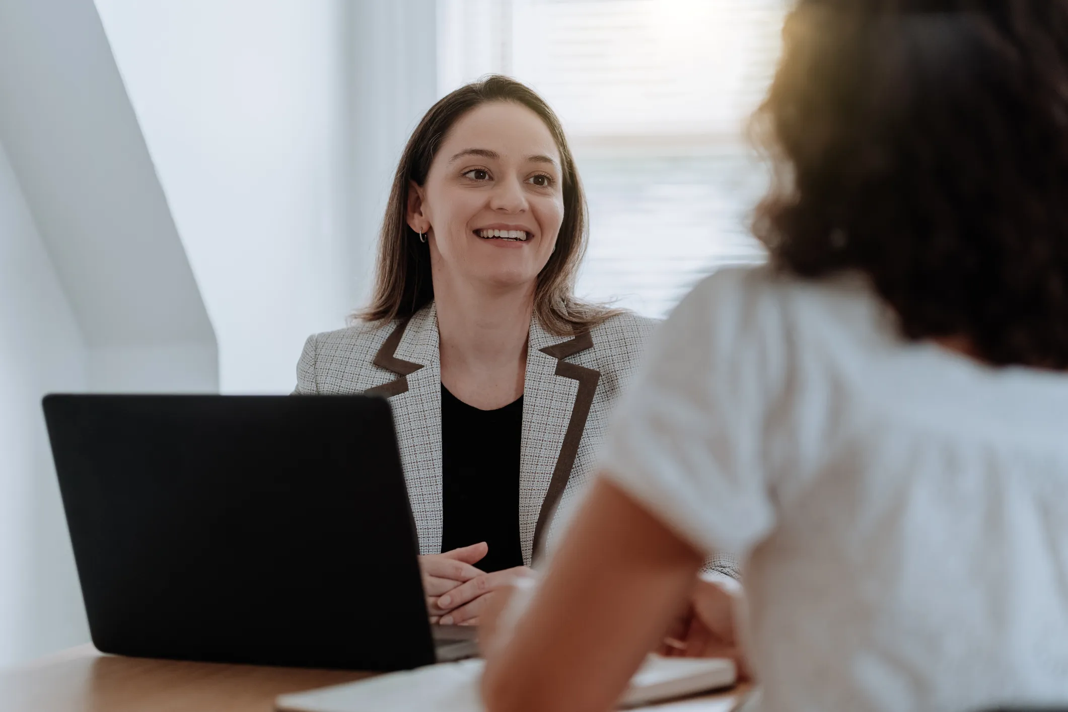 Two people are seated across from each other at a desk in a office setting