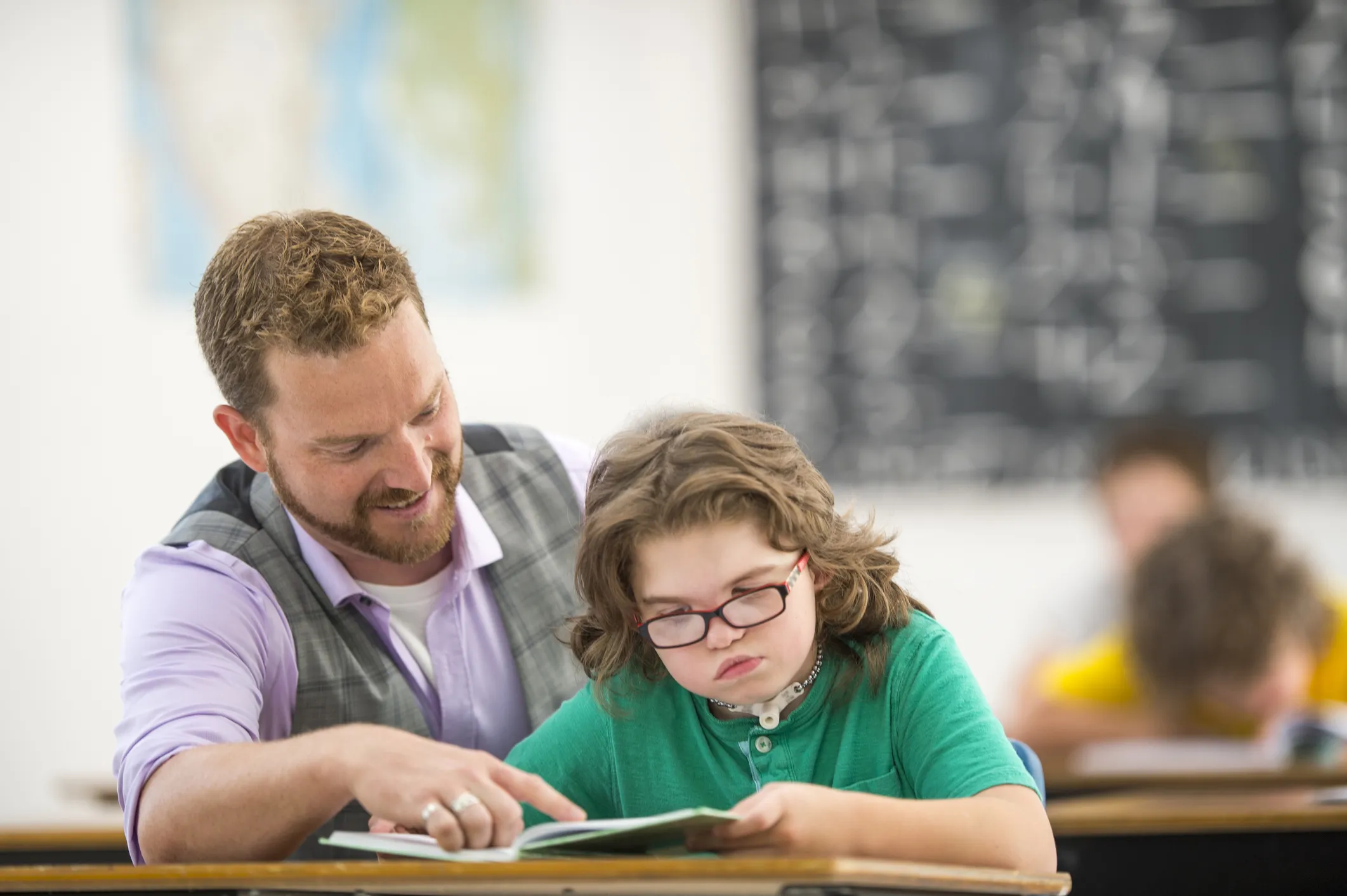 Teacher helping a child with work at a desk