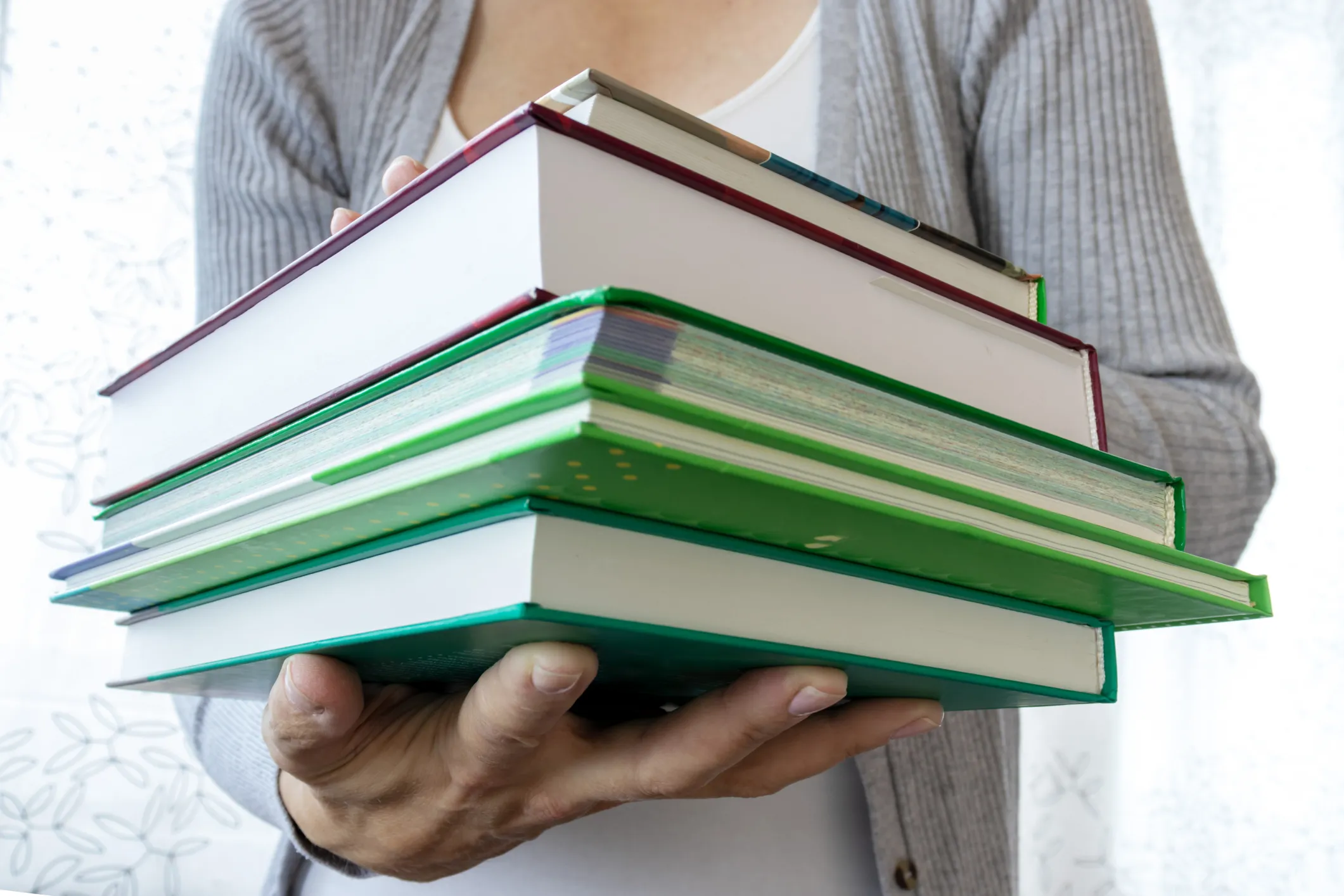 Person holding a stack of books