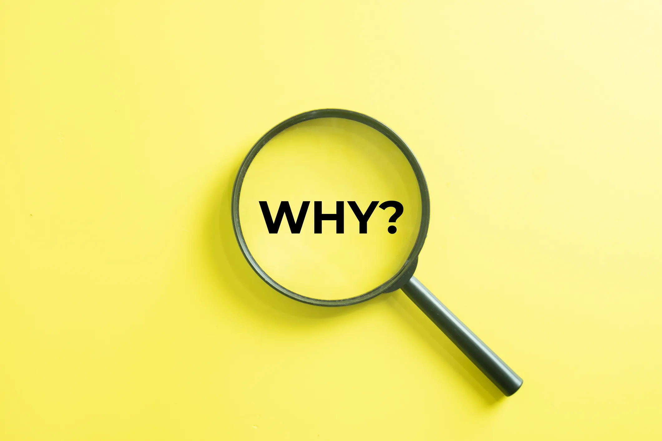 A magnifying glass on a yellow background, with the word “WHY?” visible through the lens.